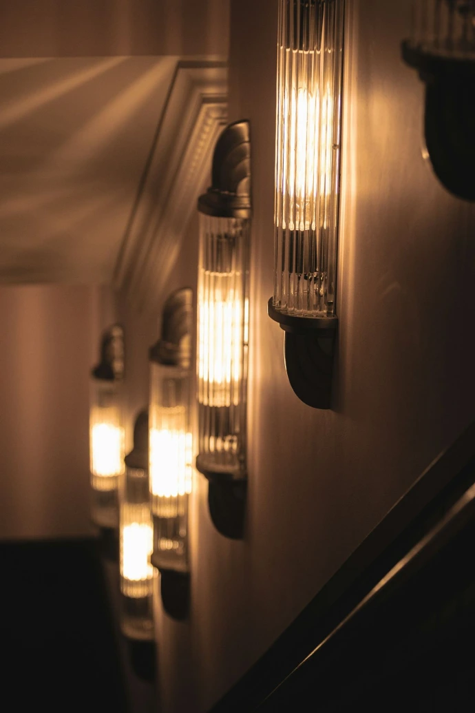 Illuminated wall sconces casting warm light in a dark hallway.